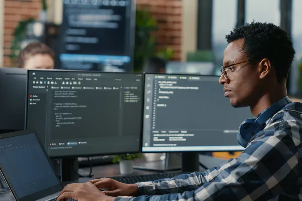 man at desk with several computer screens