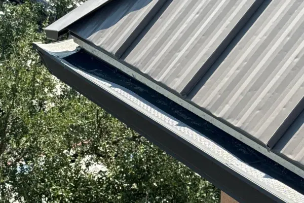 Modern metal roof with newly installed gutter guard system designed to prevent clogs, improve water drainage, and protect the home from roof and foundation damage.