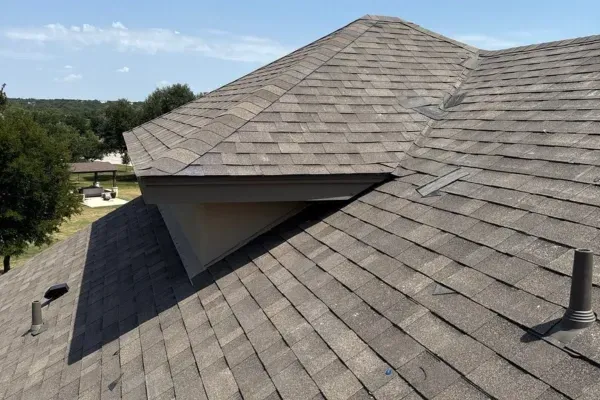 Newly installed asphalt shingle roof on a residential home under clear skies.