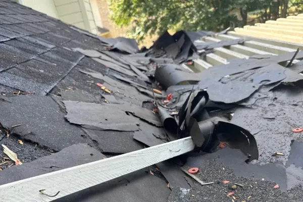 Damaged roof with torn shingles and underlayment showing need for professional roof repair and restoration.
