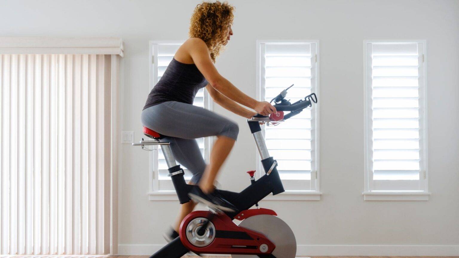 Woman using a stationary bike at home for weight loss and cardio exercise