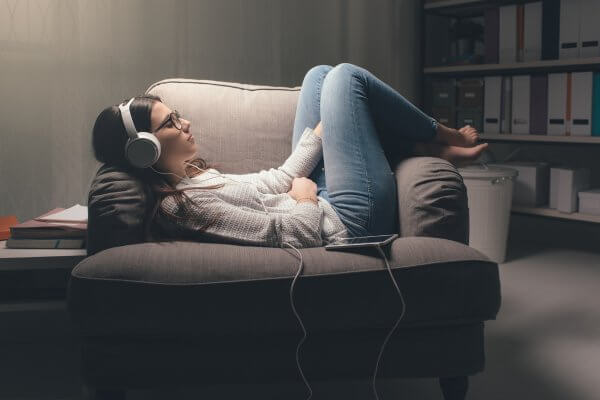 Anxious teen listening to music on couch using calming ritual for emotional regulation and stress relief