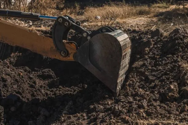 Excavator clearing brush and debris on a rural New Mexico lot
