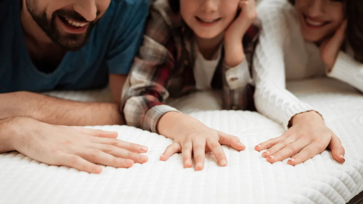 a family laying on and touching a mattress