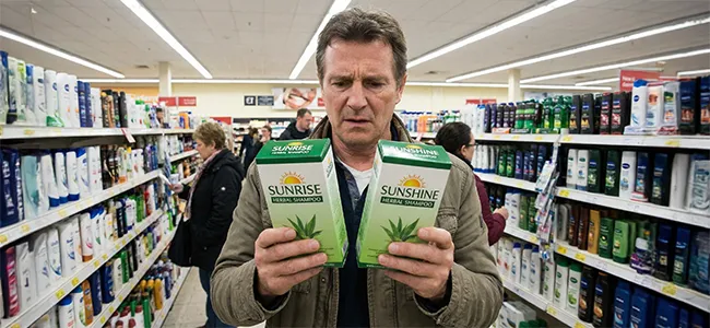 An image of a man in a shop concernedly staring at 2 products that look exactly the same