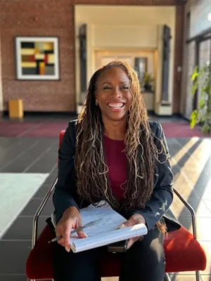 Dr. Helane seated, smiling with notepad