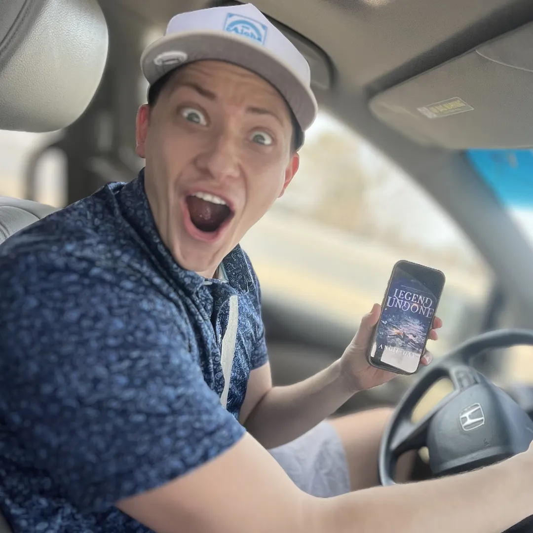 Smiling reader in car holding Legend Undone clean fantasy romance ebook on phone