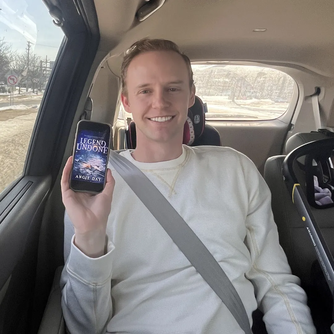 Reader in car showing Legend Undone clean fantasy romance ebook on phone
