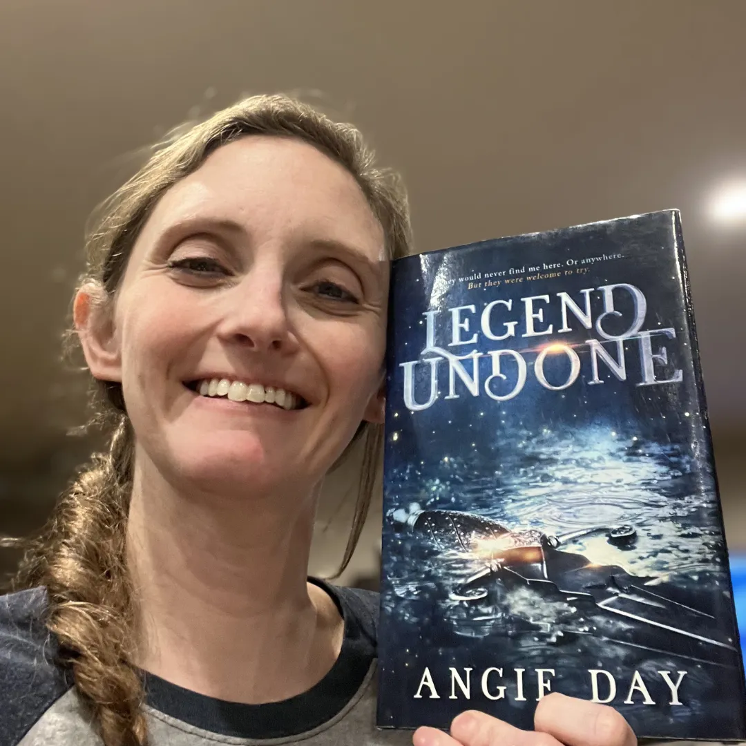 Smiling reader holding Legend Undone clean romantasy paperback book