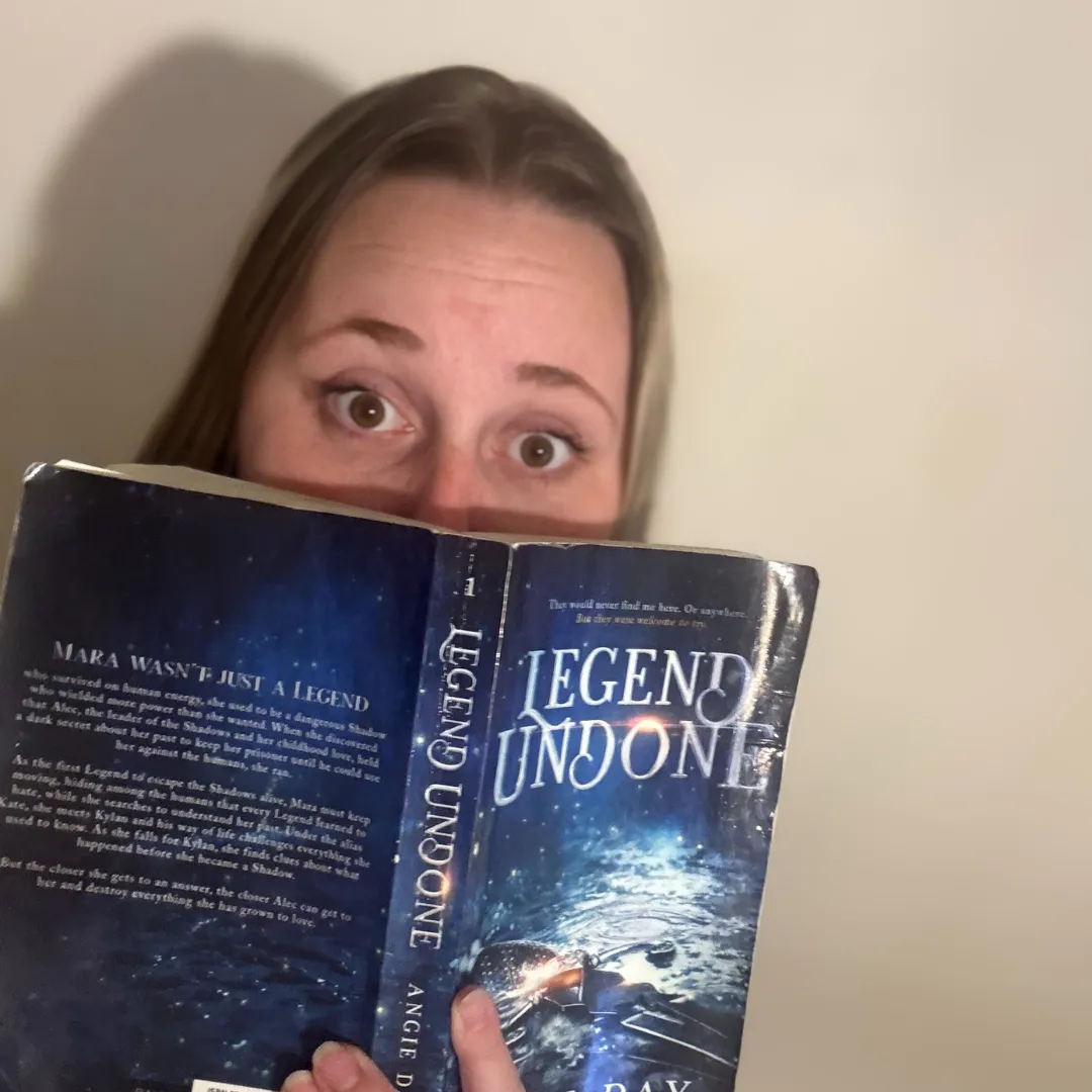 Reader holding open copy of Legend Undone clean fantasy romance novel