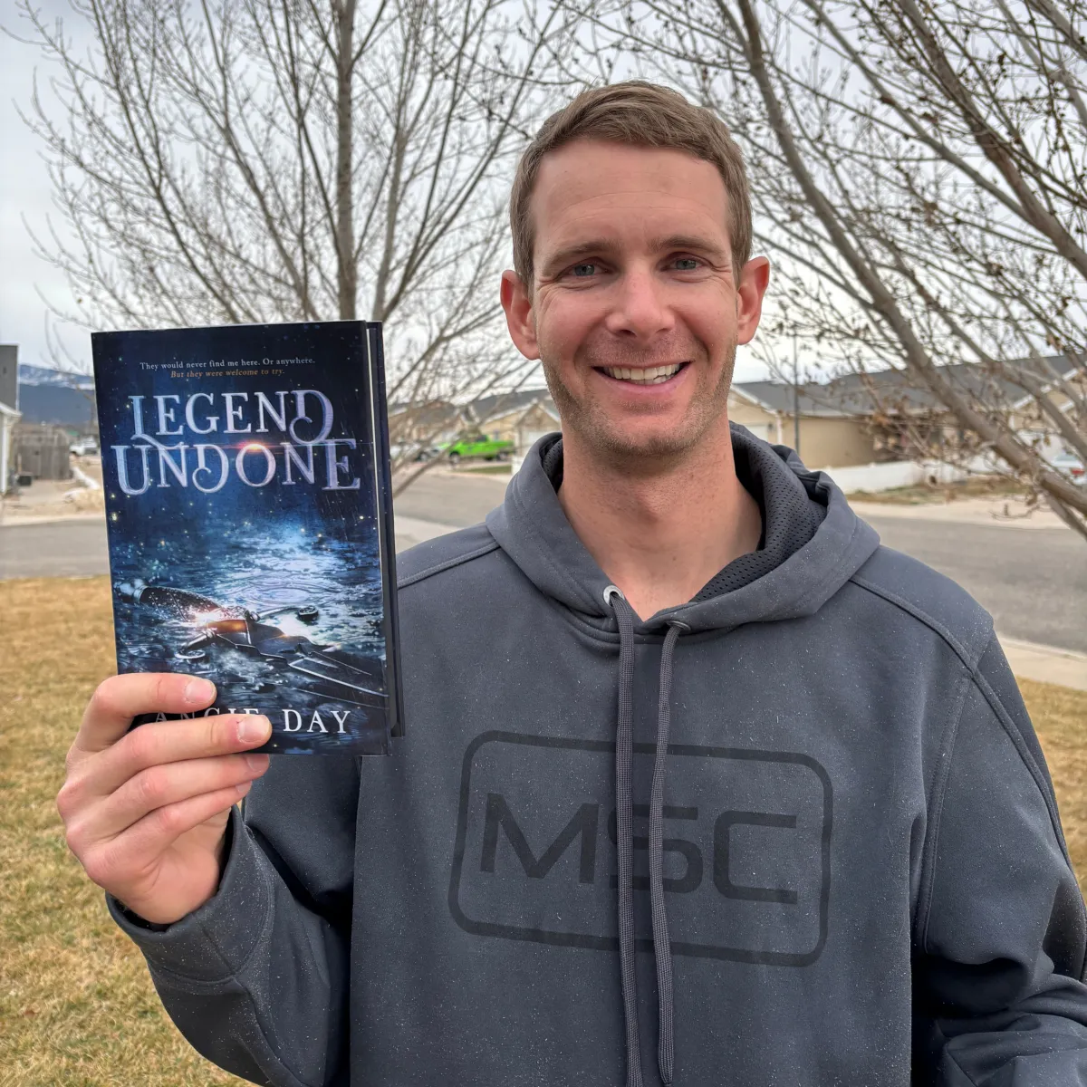 Reader outdoors holding Legend Undone clean fantasy romance paperback