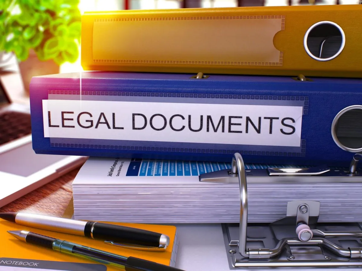 Several binders stacked with large blue binder showing the words legal documents in all capital letters
