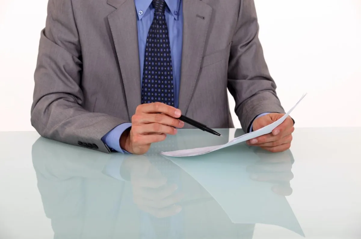 A man in a suit closely reviewing a document.
