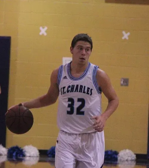 High school basketball player Casey Teson dribbling the ball for St. Charles High School during a varsity game.