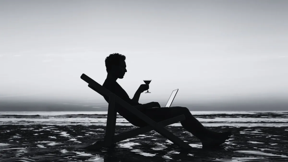  An image of a person relaxing on a beautiful beach with a laptop and a cocktail nearby, symbolizing the idea of achieving freedom and success by working smarter and not harder. 