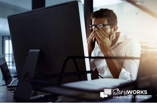 frustrated business owner with hands in face in front of computer
