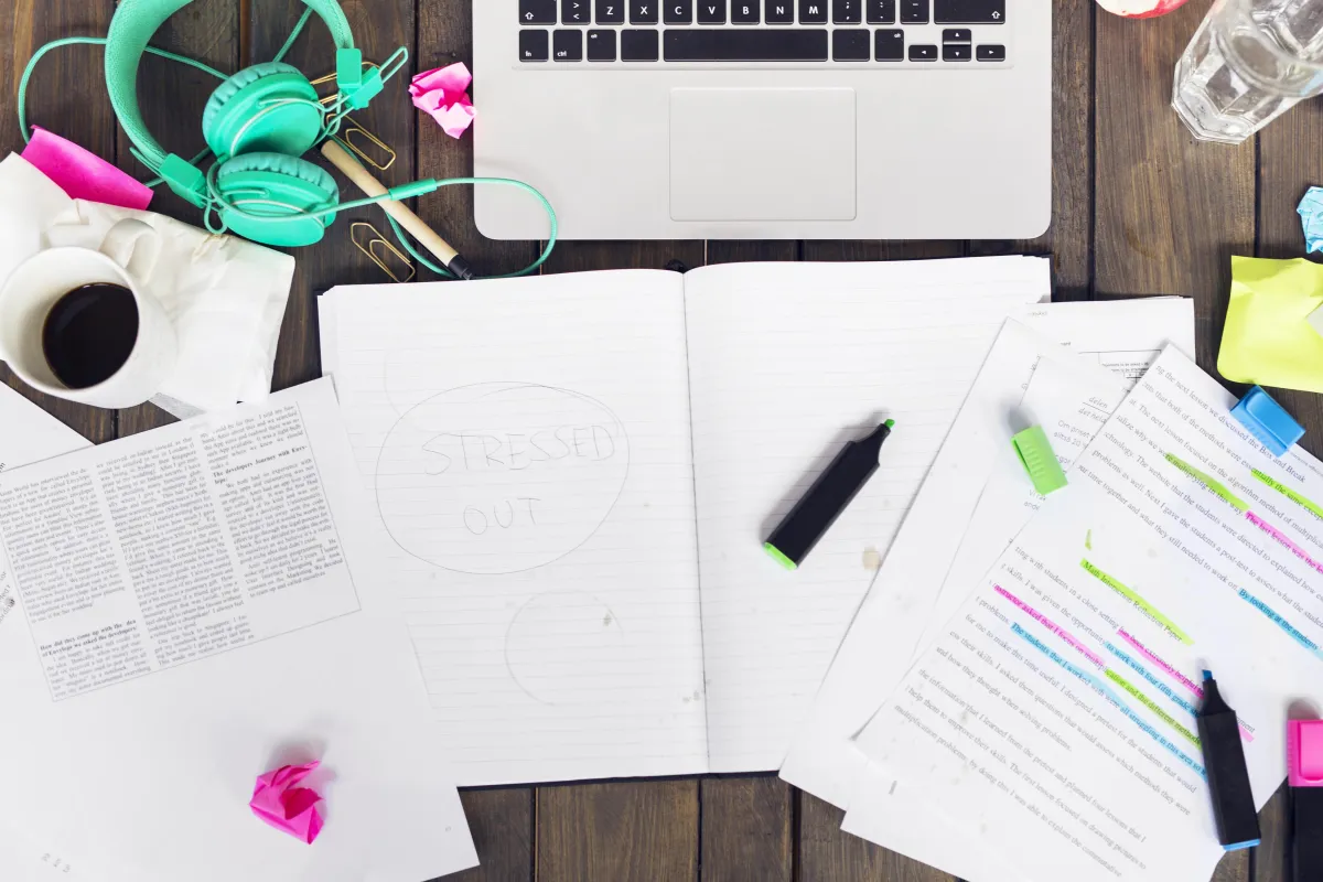 A cluttered desk: open planner with highlighters
