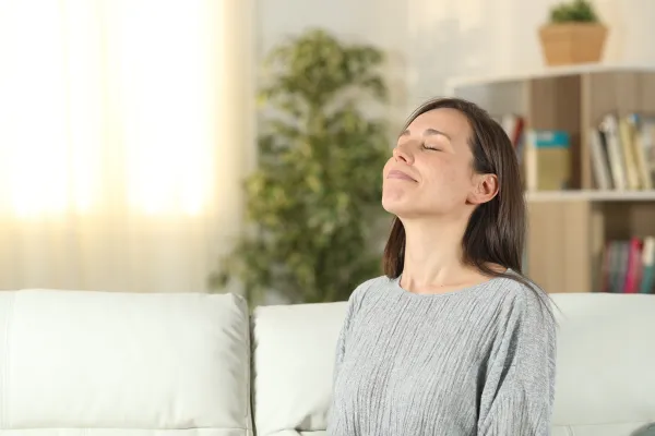 A woman sitting on the couch exhaling in relief