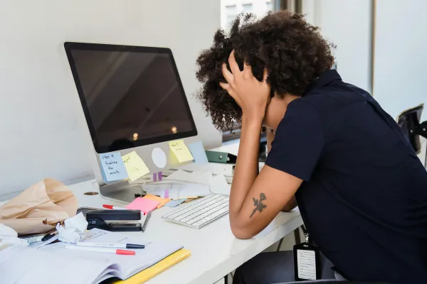 A person sitting at a desk, deep in thought, hesitating over a decision they’ve been avoiding.