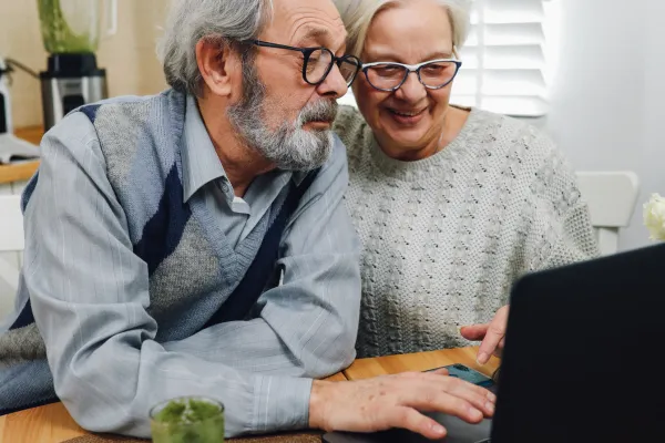 A couple sitting together, reviewing a document on their laptop, preparing to sign it digitally for remote online notarization.