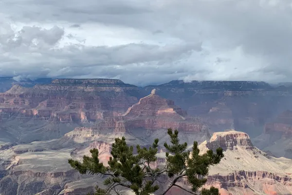 A serene rainbow over the Grand Canyon, with empty lookout points and soft light filling the vast canyon below, evoking stillness and reflection.