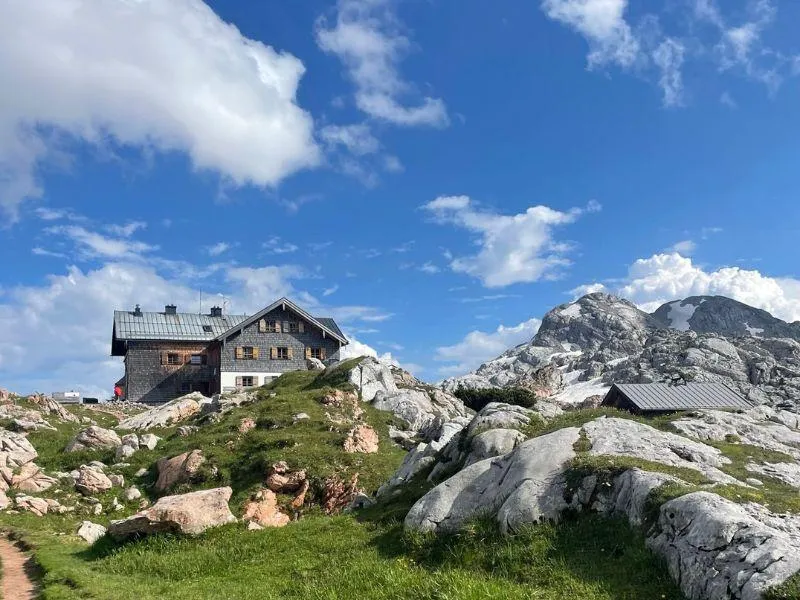 Rocky hiking trail leading to a remote mountain hut surrounded by untouched alpine nature
