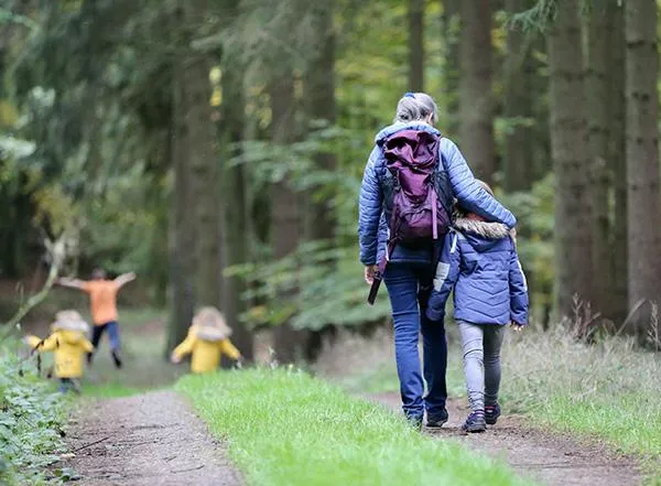 Mom walks with kids through the woods