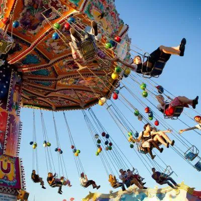 Colorful carousel ride at Oktoberfest Munich spinning under a bright blue sky, capturing the festive atmosphere of the world’s largest beer festival.