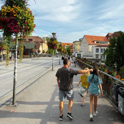 Family, a Dad and two girls, walks through an European city on a broad sidewalk