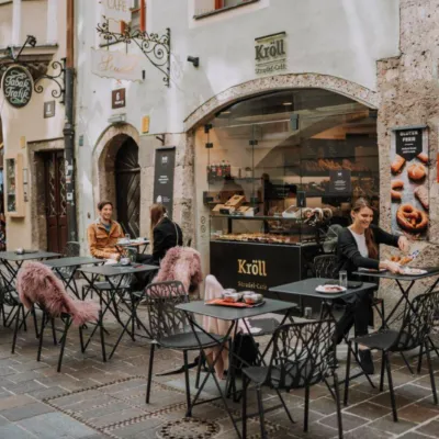 A couple is sitting outside at tables of a beautiful old bakery and cafe.
