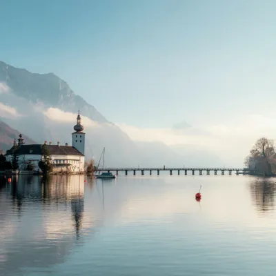 Beautiful lake in the alps with a church in the background and a bridge, surrounded by clouds