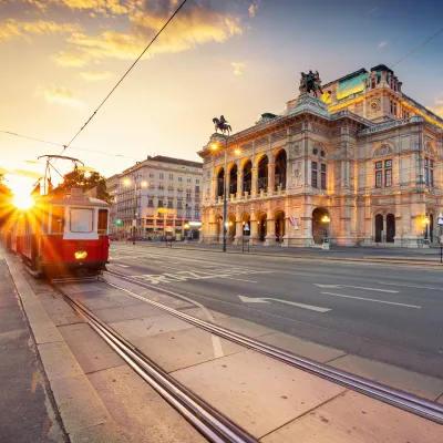 Tram in Old town Vienna in front of traditional buildings and the sunset in the background.