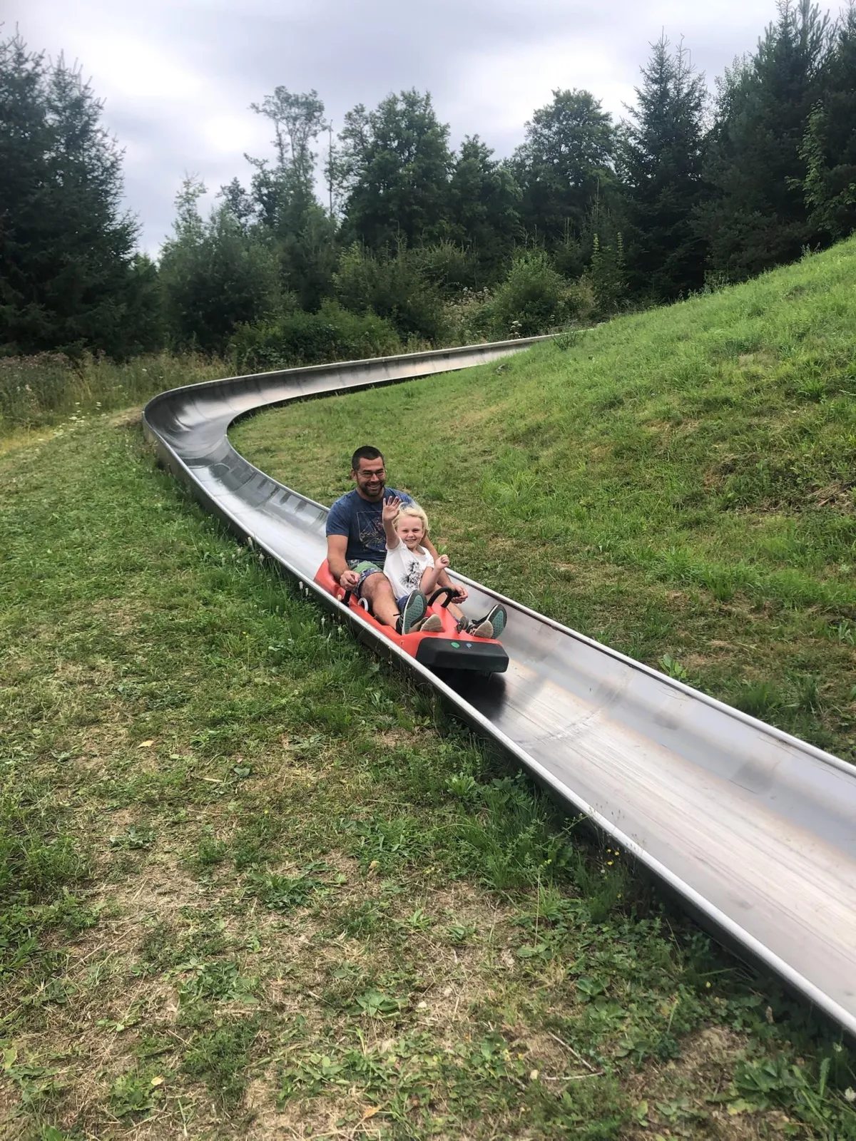 Father and child riding a summer bob sled on a hillside in Europe, having fun together