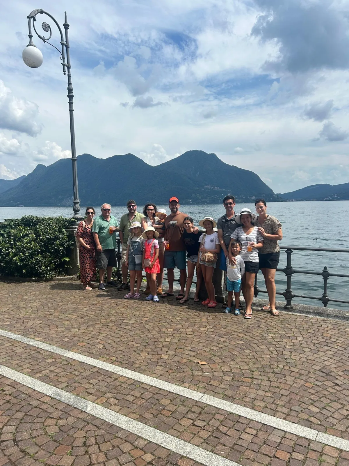 Large family posing in front of a lake surrounded by European mountains during a vacation