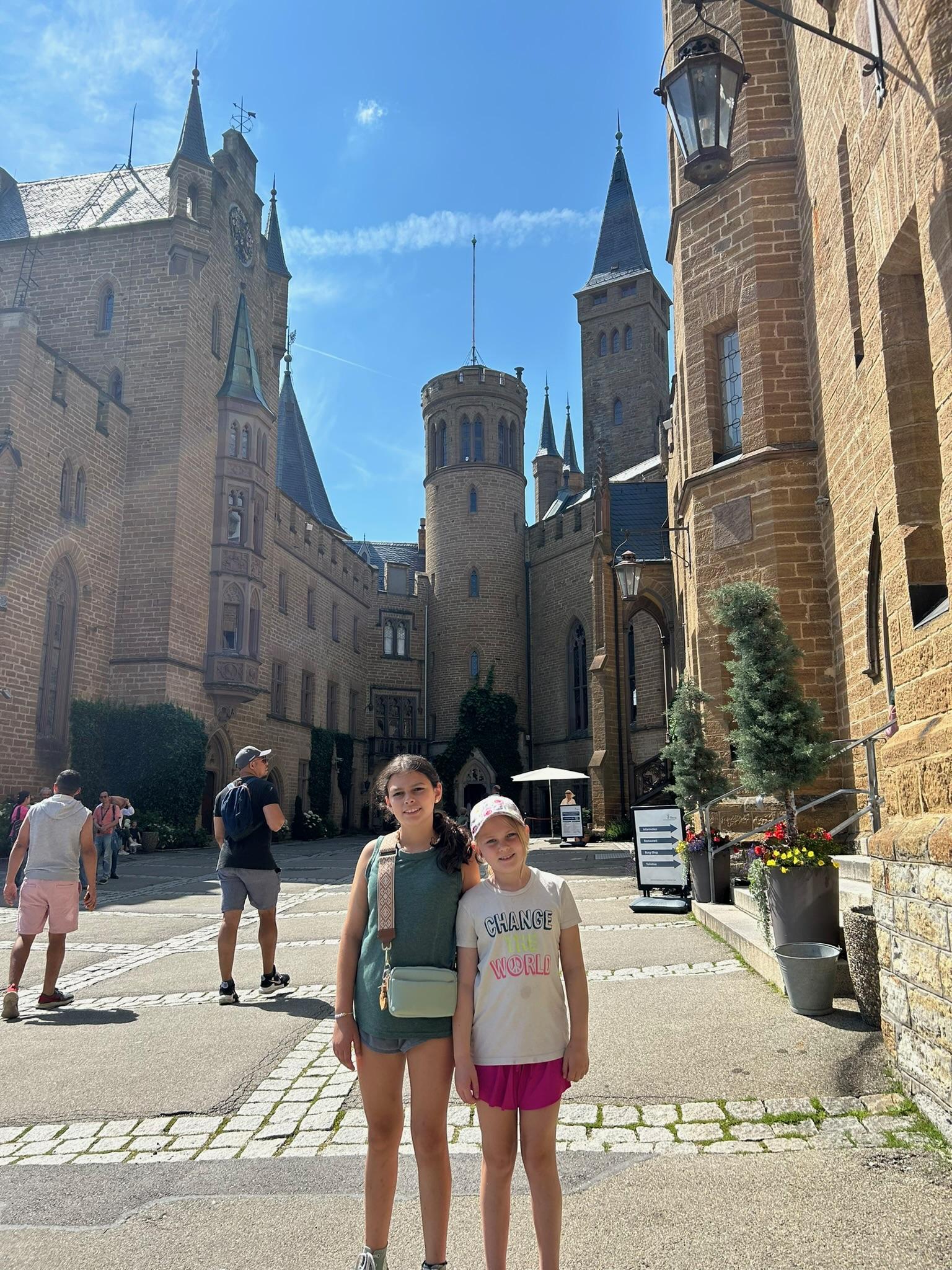 Family standing on a castle terrace with a European castle and scenic views in the background