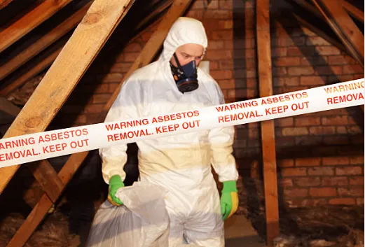 A man in a protective suit is standing in an attic.