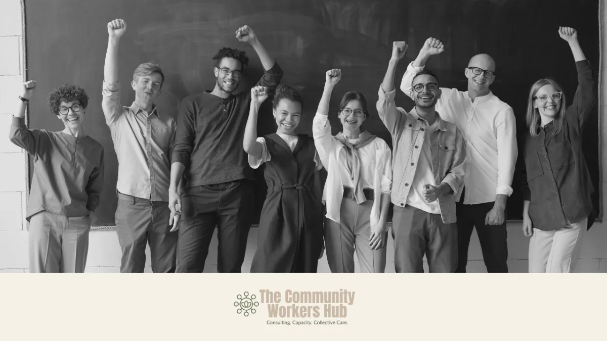 A diverse group of people stand together in front of a chalkboard, smiling and raising their fists in a gesture of solidarity and empowerment. The black-and-white image conveys collective action, confidence, and shared purpose. The Community Workers Hub logo appears at the bottom of the image.