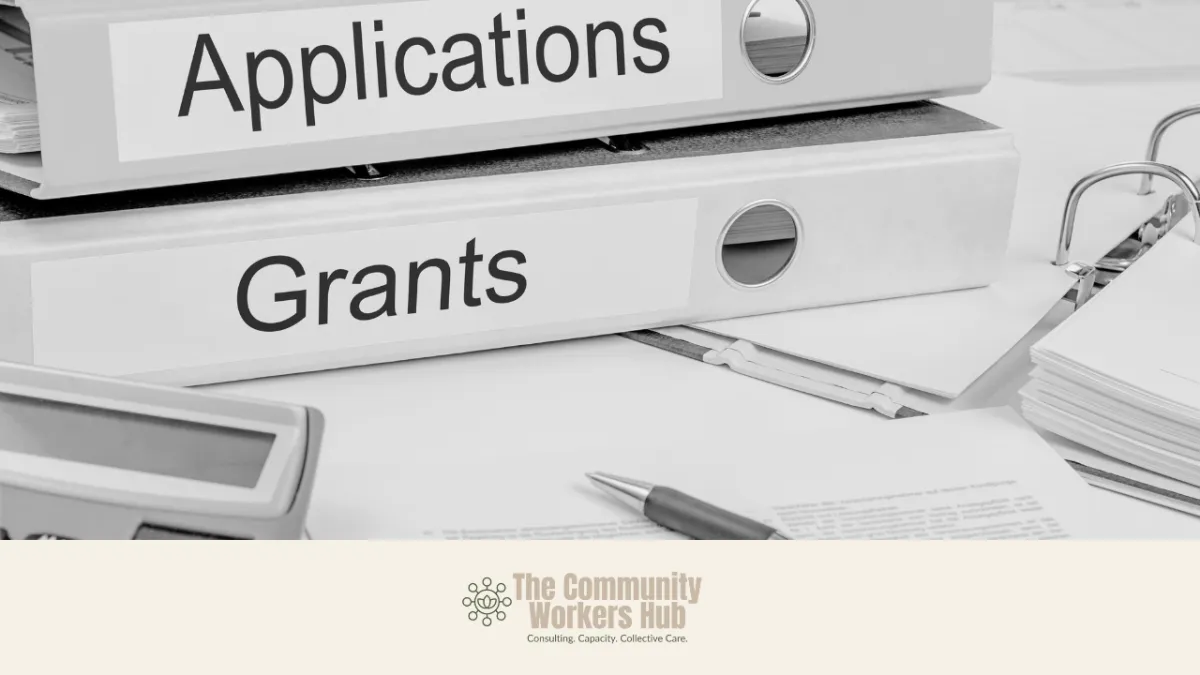 Two labelled ring binders stacked on a desk read “Applications” and “Grants,” with paperwork, a pen, and office items nearby. The black-and-white image represents grant writing, administration, and funding processes. The Community Workers Hub logo appears at the bottom of the image.