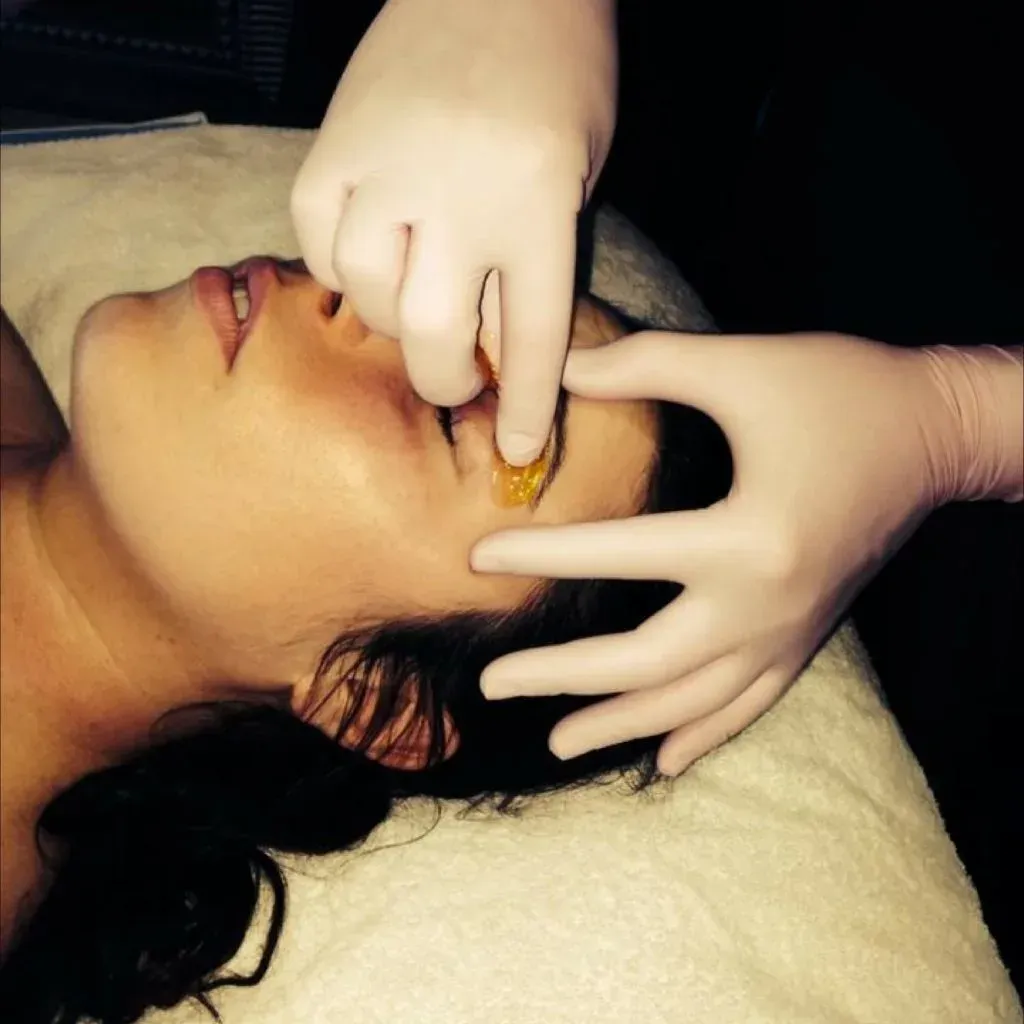 Esthetician performing gentle eyebrow sugaring for precise shaping
