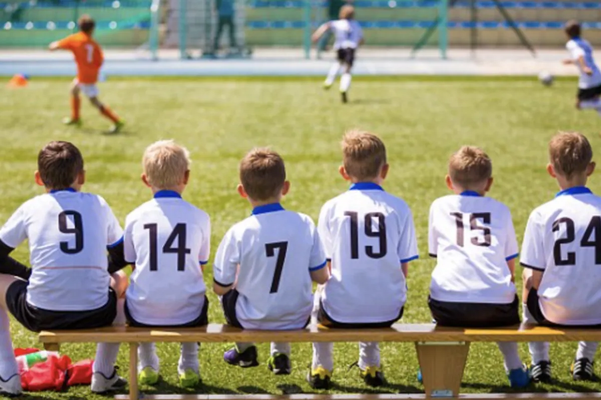 Team of kids sitting on the bench in a football match