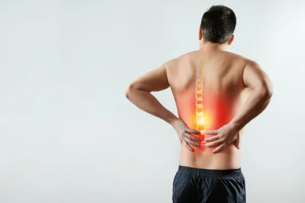 Man grimacing in discomfort, clutching his lower back, highlighting the need for effective back pain treatment.