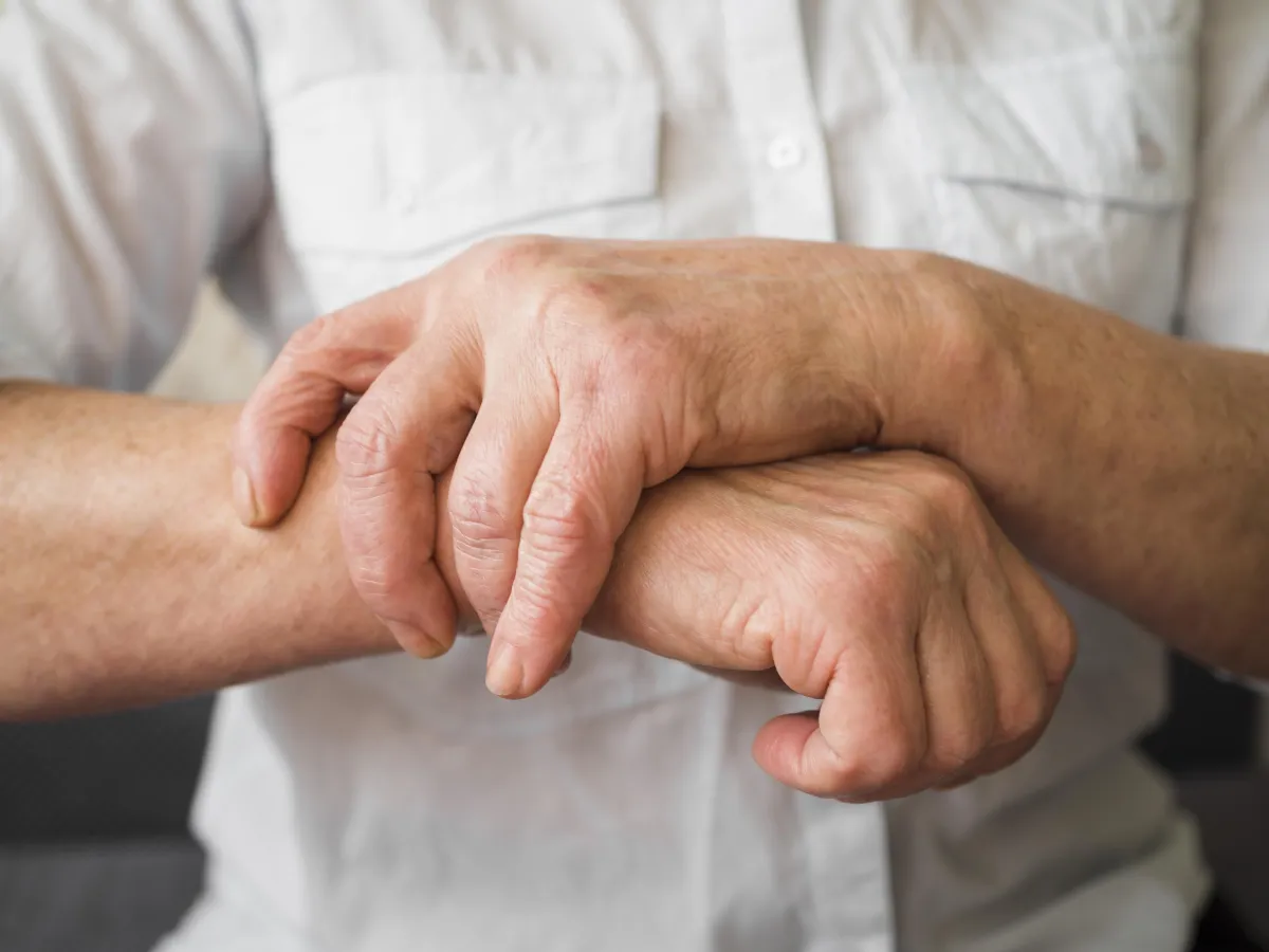 Person holding wrist and forearm in pain, illustrating nerve pain, joint discomfort, or neuropathy symptoms in the arm