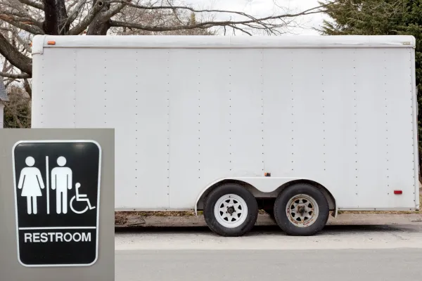 Luxury portable restroom trailer with restroom sign at an outdoor wedding event 