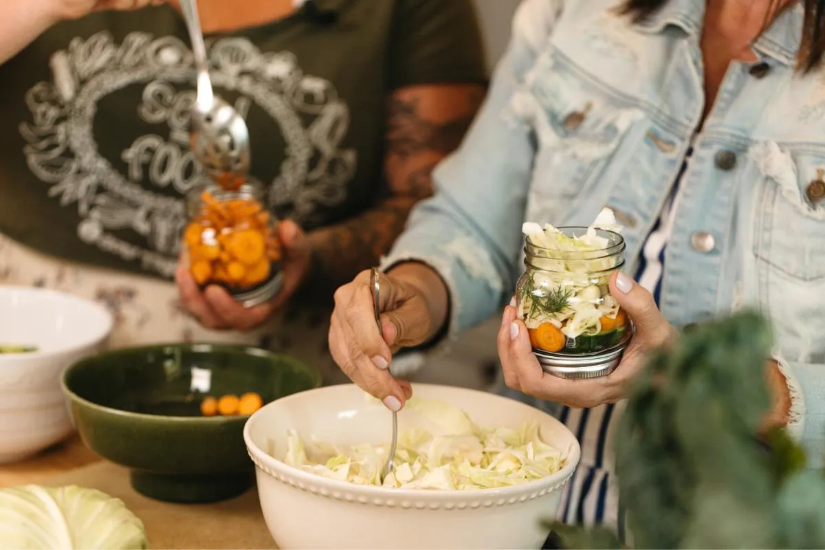 Hands-on lacto-fermentation activity with guests filling jars with seasonal vegetables and brine