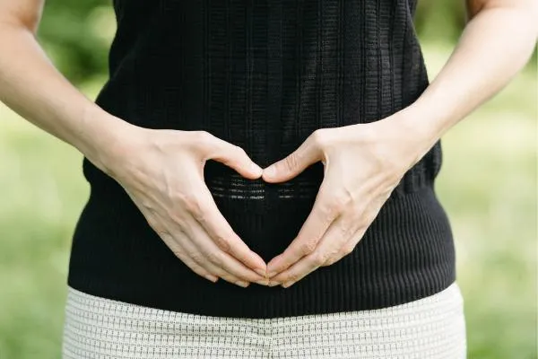 Hands forming a heart on the stomach representing love for gut health and digestive care.