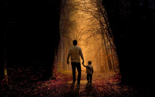 Father and son walking on a forest path with autumn leaves, symbolizing life's journey and growth through vulnerability.