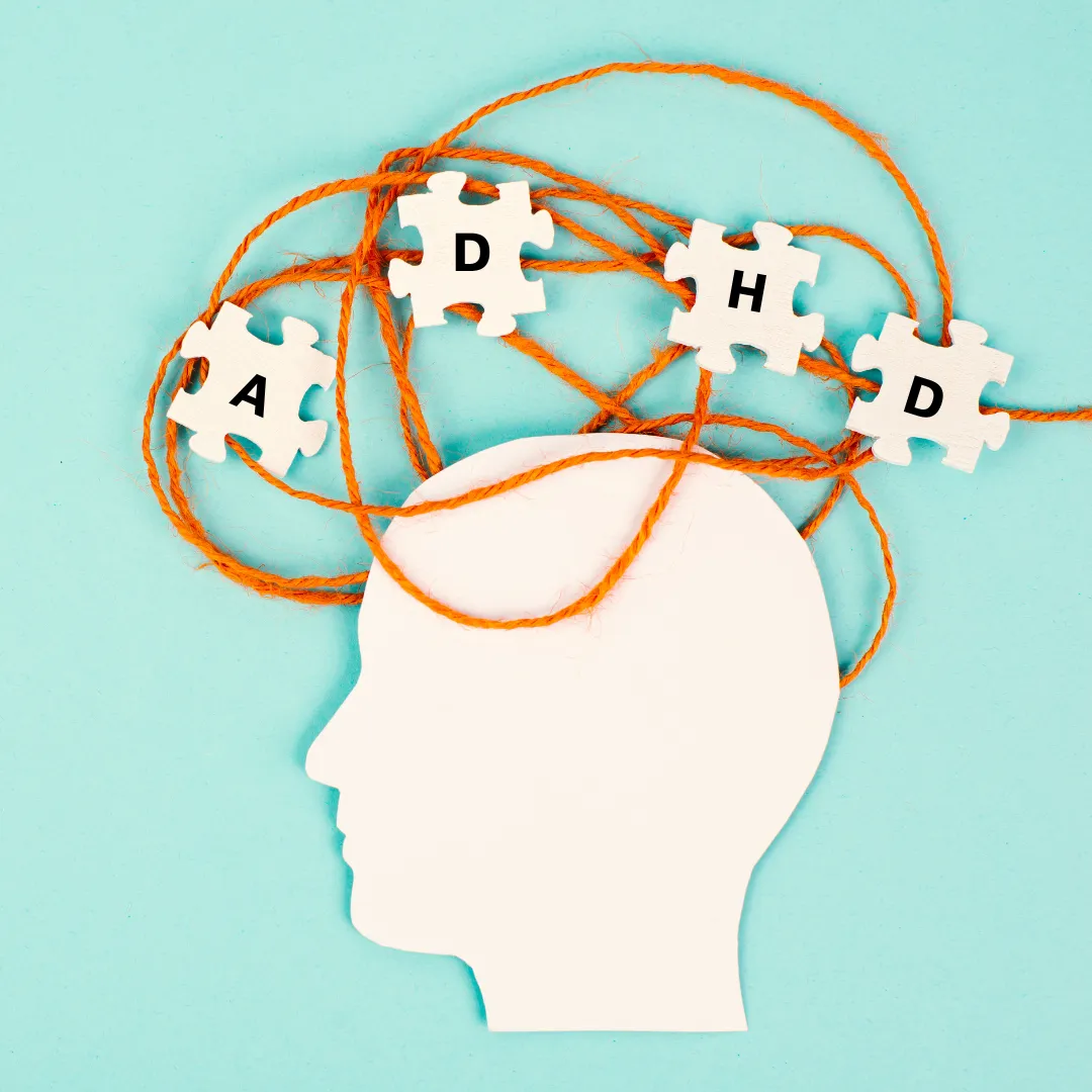 Photo for Ignite Change Makers' Blog on Unlocking ADHD, by Gail Suitor. It is a white silhouette of a head on a light blue background with four white puzzle pieces above with a letter on each one spelling out ADHD, with an orange strand of yarn tangled behind them.