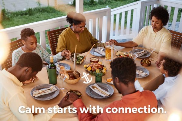 A family holding hands around a Thanksgiving table, representing calm connection and gratitude.