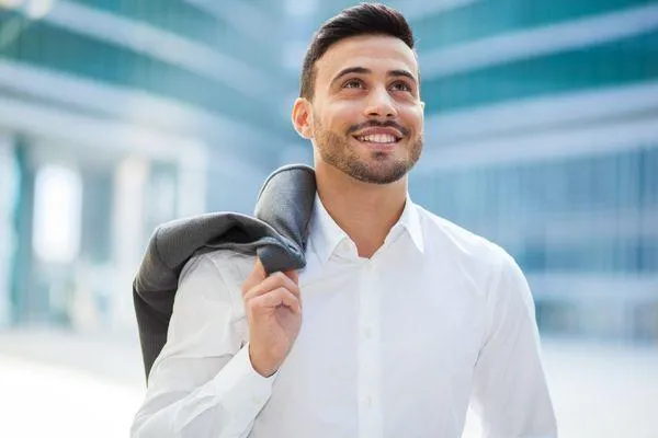 a man smiling while holding his coat on the side