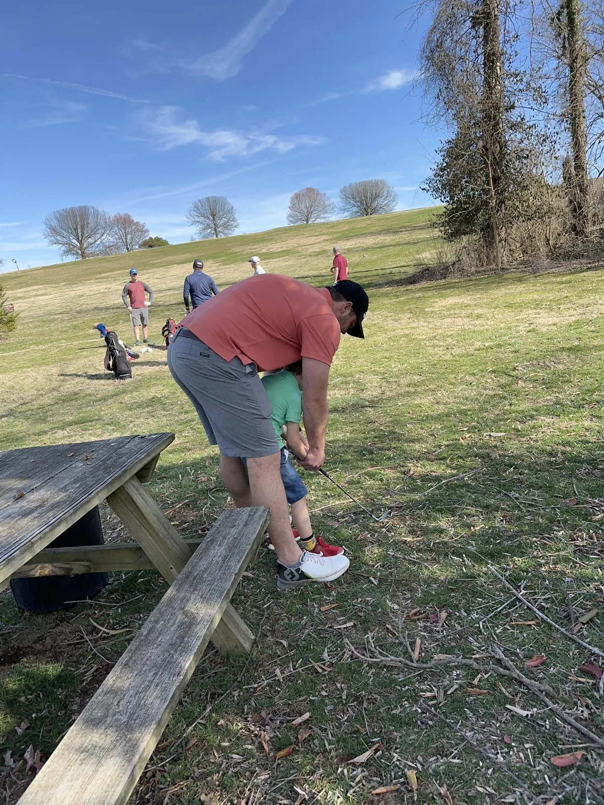 Man teaches son to play golf. 